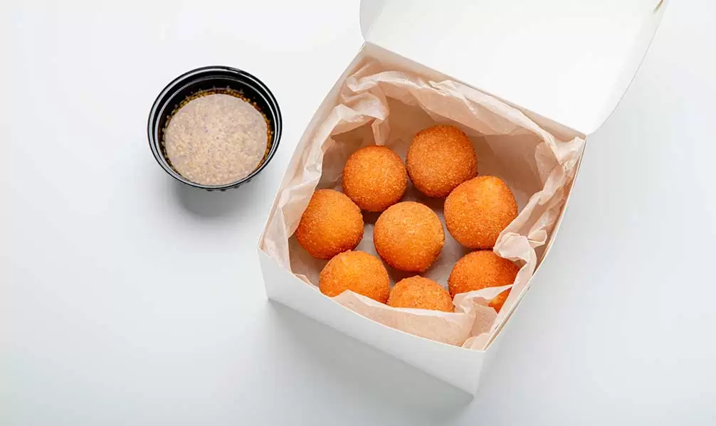 Bolista de patatas con salsa en una tarrina salsera para delivery