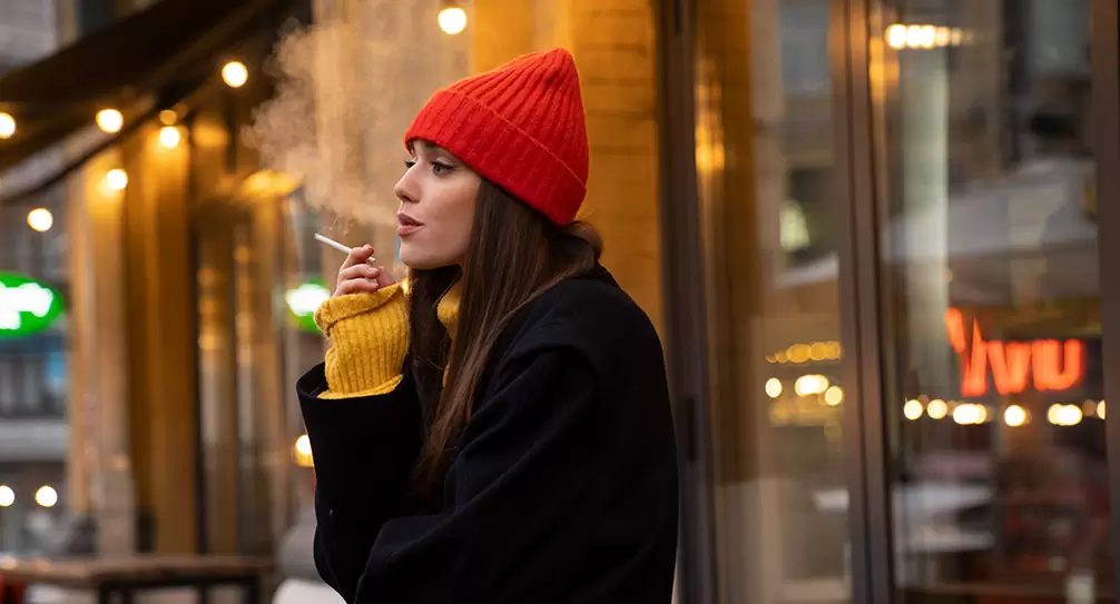Mujer con un cigarro en la mano fumando en la terraza de un bar