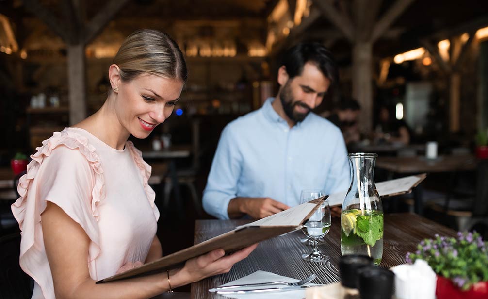 Pareja en restaurante leyendo la carta del menú de tamaño medio