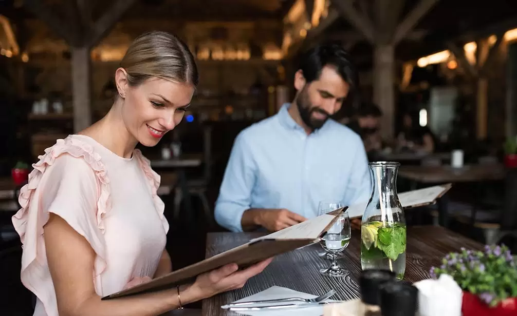 Pareja en restaurante leyendo la carta del menú de tamaño medio